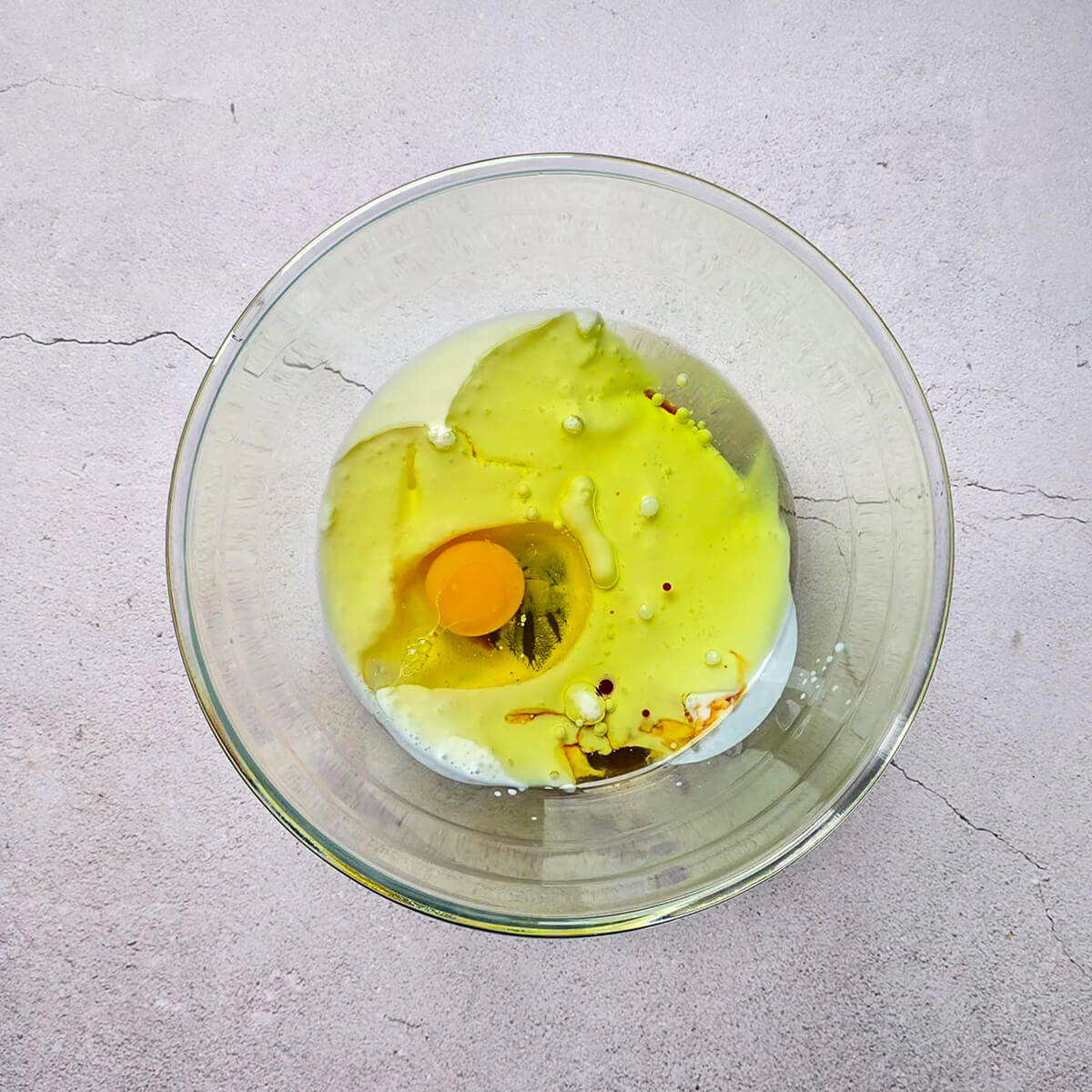 Un saladier contenant un mélange d'œufs, huile et lait pour faire des muffins.