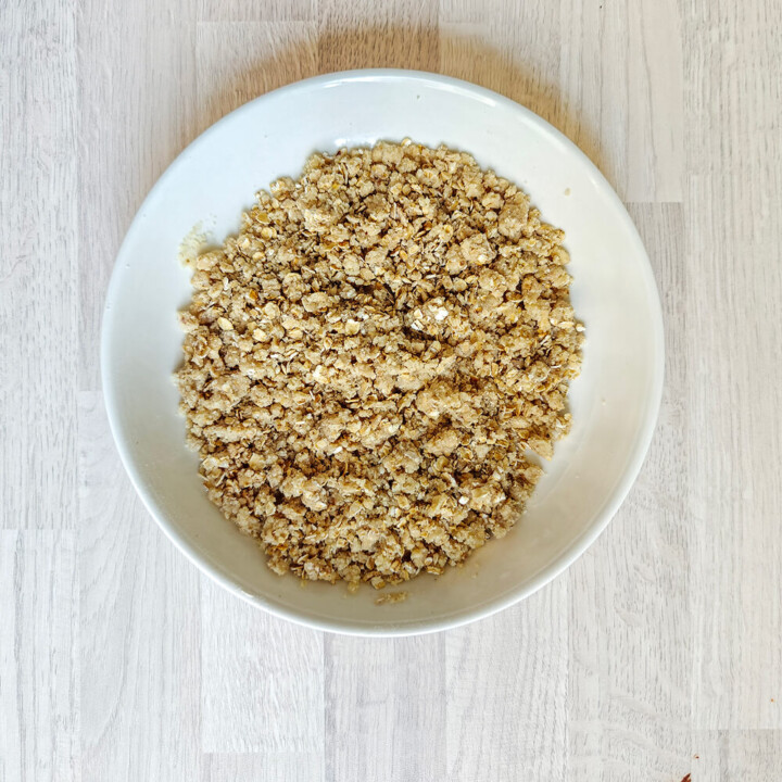 Pommes coupées en petits dés réguliers dans un bol en inox, saupoudrées de cannelle pour une base de crumble aux pommes sans sucre ajouté.