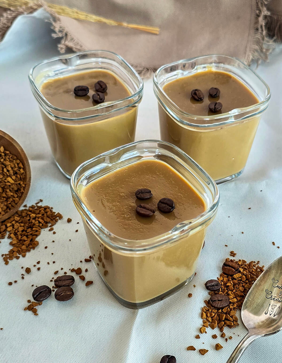 Des crèmes dessert au café soluble, grains de café et café soluble sur le coté.