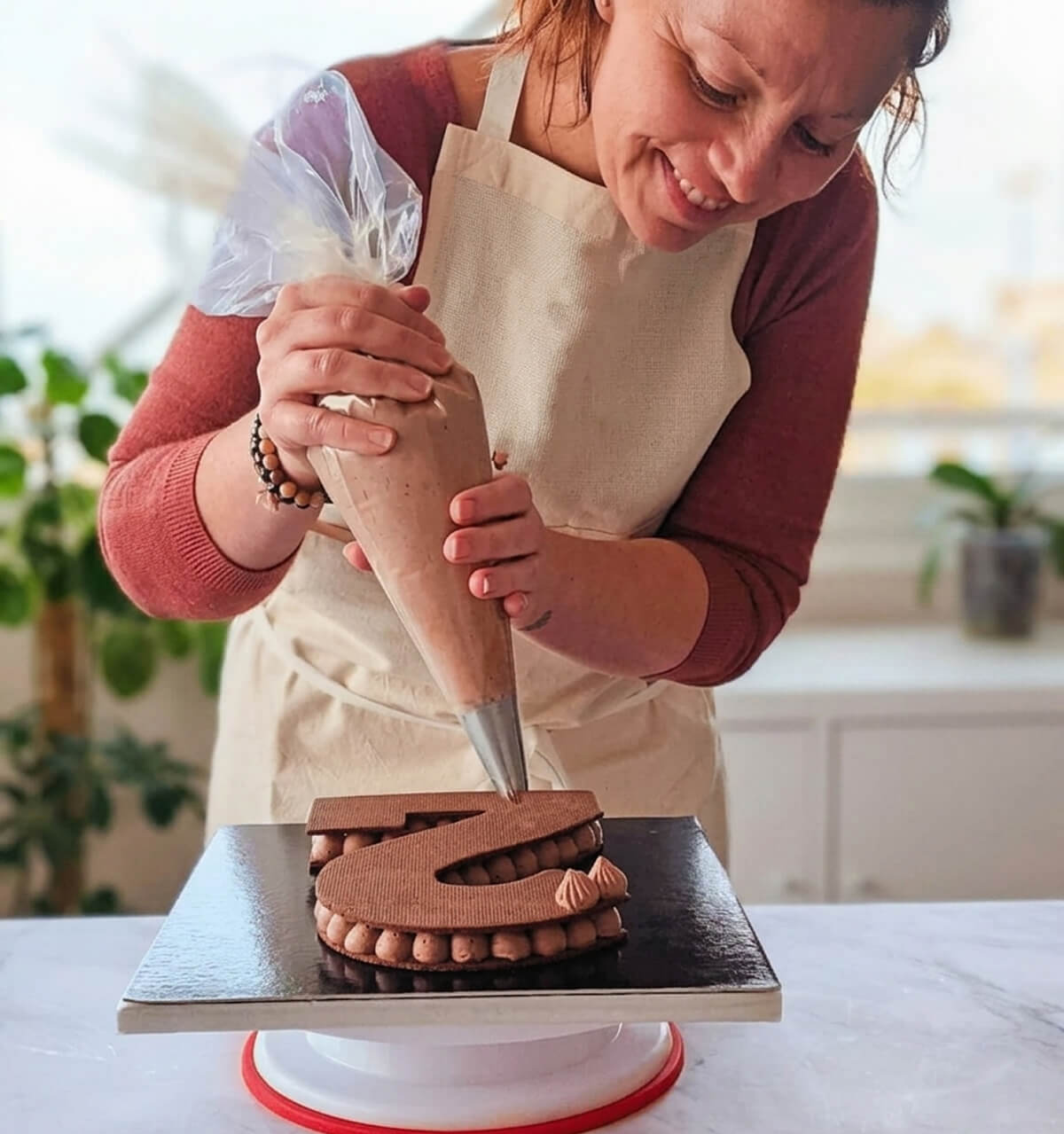 Sandrine, blogueuse, entrain de pocher de la chantilly mascarpone, sur un number cake 2.