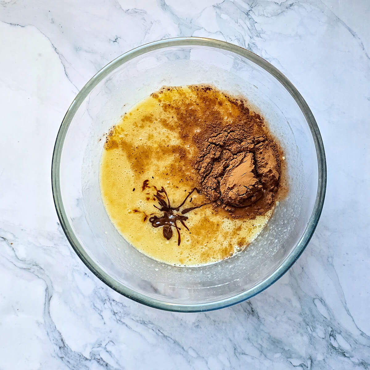 De la poudre de cacao et du chocolat pâtissier fondu dans un mélange liquide pour un banana bread.