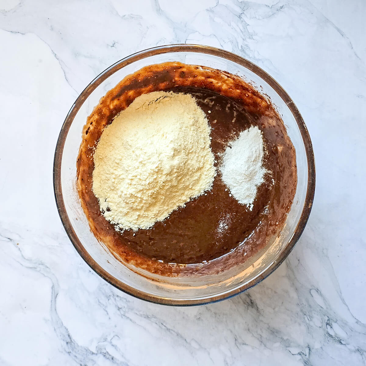 Ajout de farine, de levure et de sel dans un récipient pour réaliser un banana bread.