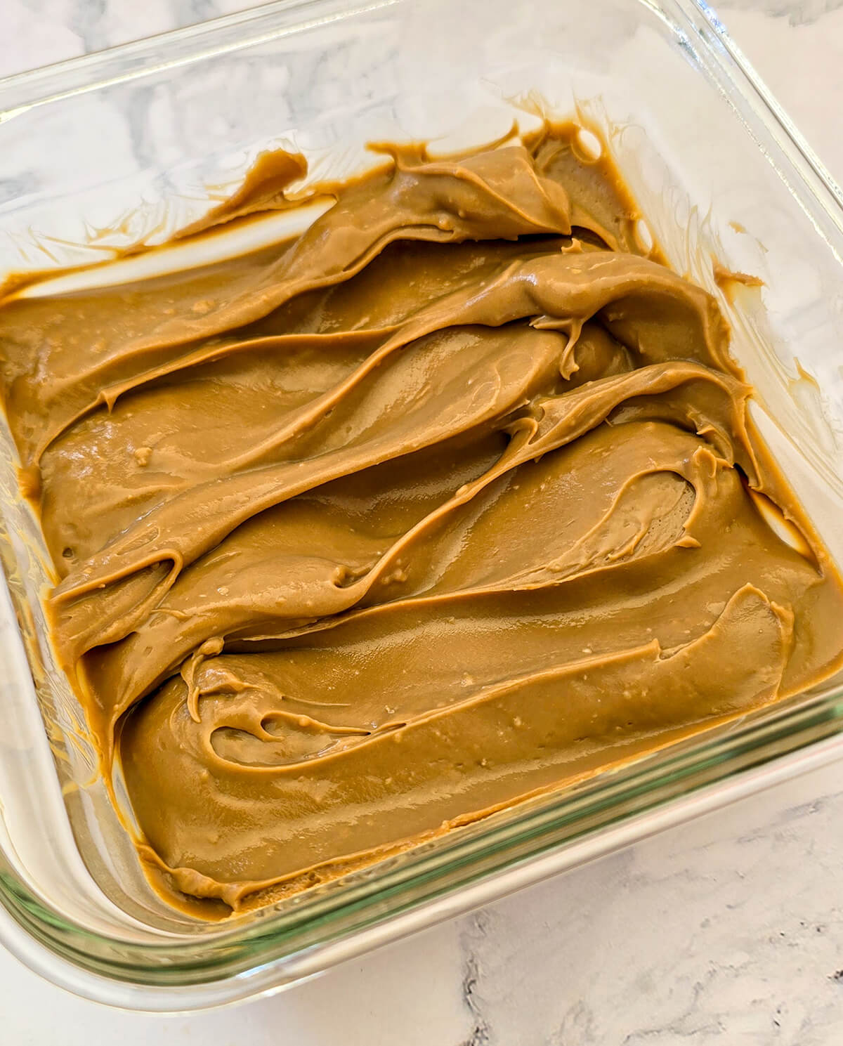 Un plat en verre carré rempli de ganache café épais et onctueux.