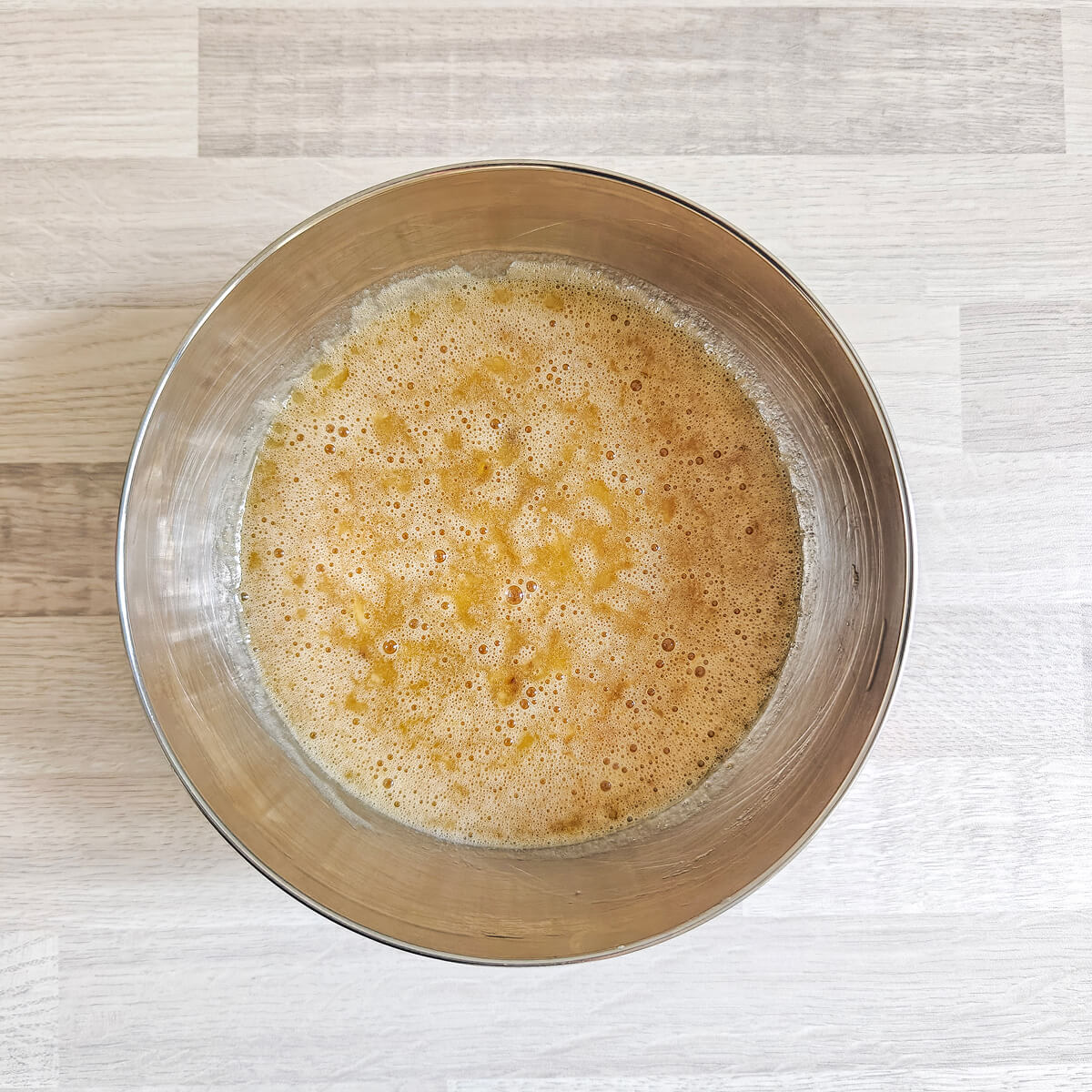 Vue de dessus d'un bol en acier inoxydable contenant les ingrédients liquides pour un banana bread.