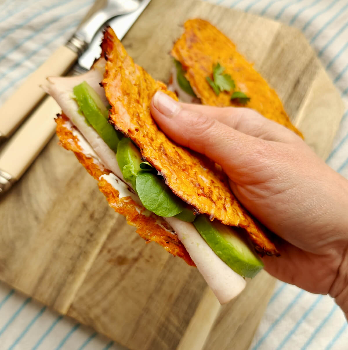 Un main tenant un wrap carotte avec des tranches d'avocat, une tranche de blanc de poulet.