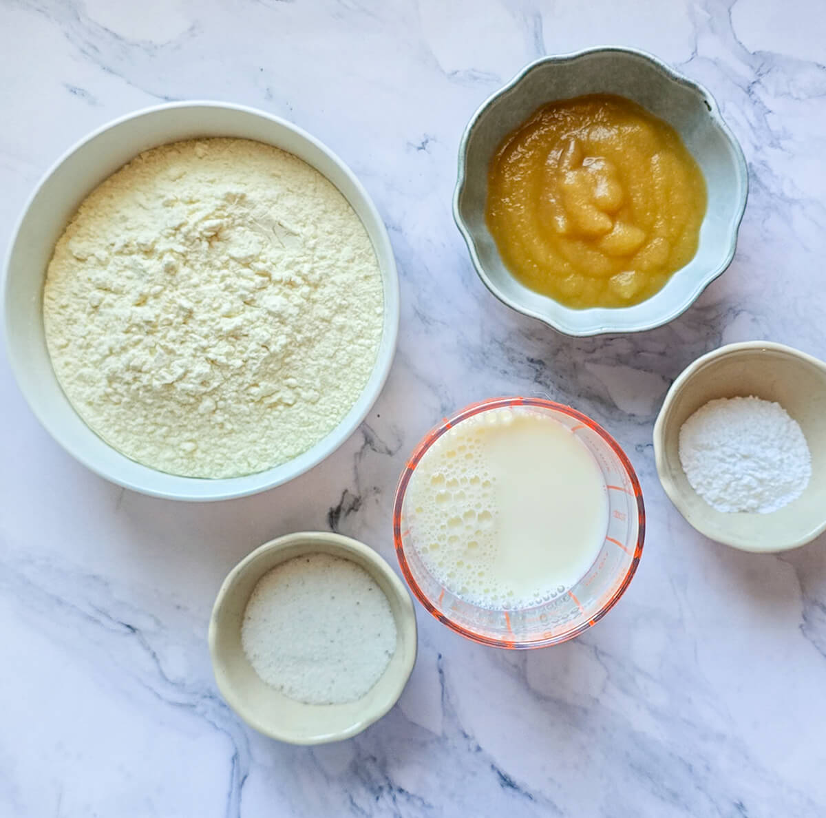 Des ingrédients pour préparer des pancakes sur un fond blanc marbré.