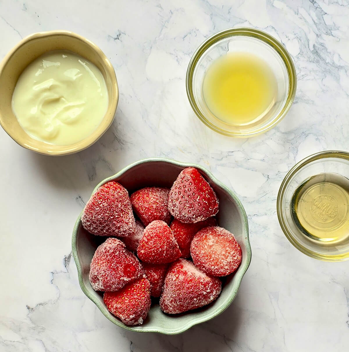 Des ingrédients pour réaliser un sorbet à la fraise, sur un fond blanc marbré.