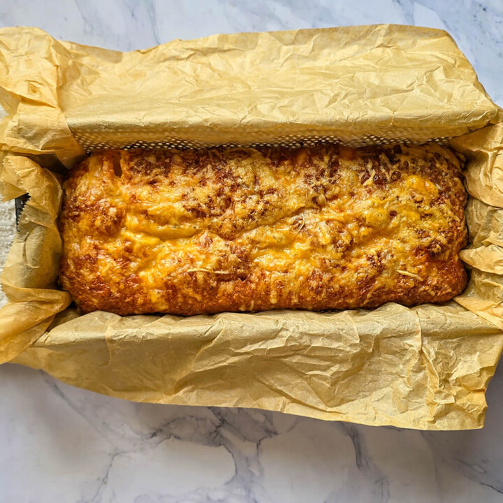 Un cake salé dans un moule à la sortie du four, sur une surface blanche marbrée.