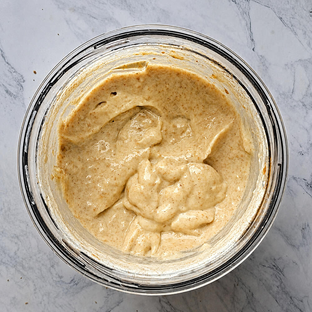 Vue plongeante dans le bol d'un mixeur montrant le mélange de banane, biscuit et crème parfaitement mixé pour obtenir une texture de glace onctueuse et homogène.