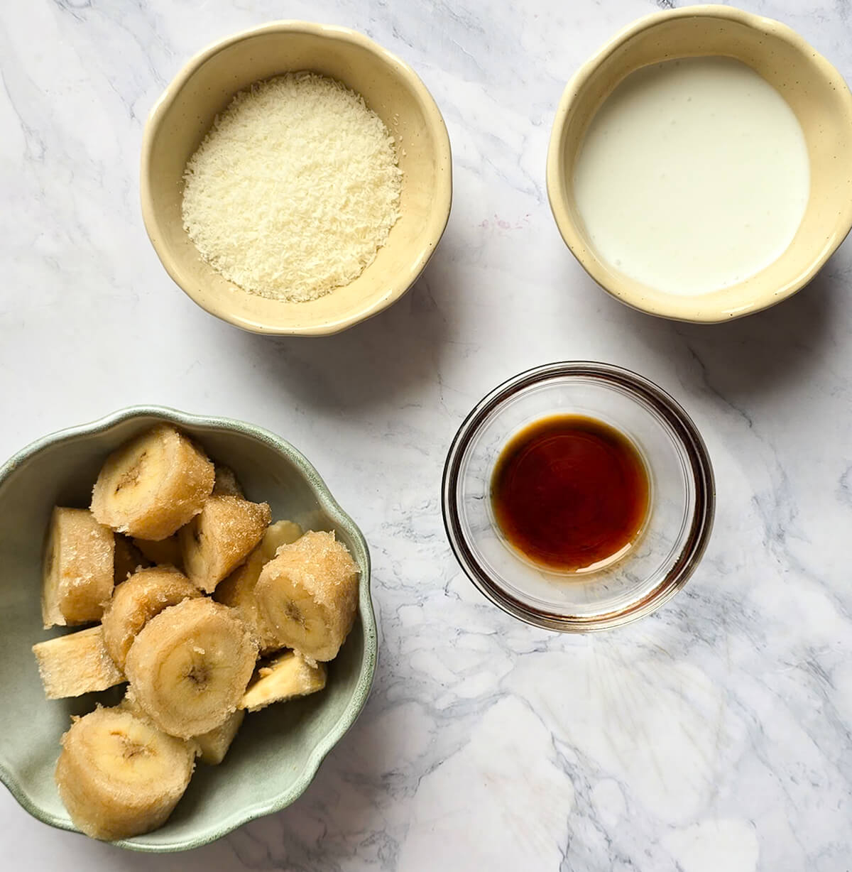 Des ingrédients pour préparer une glace à la banane coco, sur un fond blanc marbré