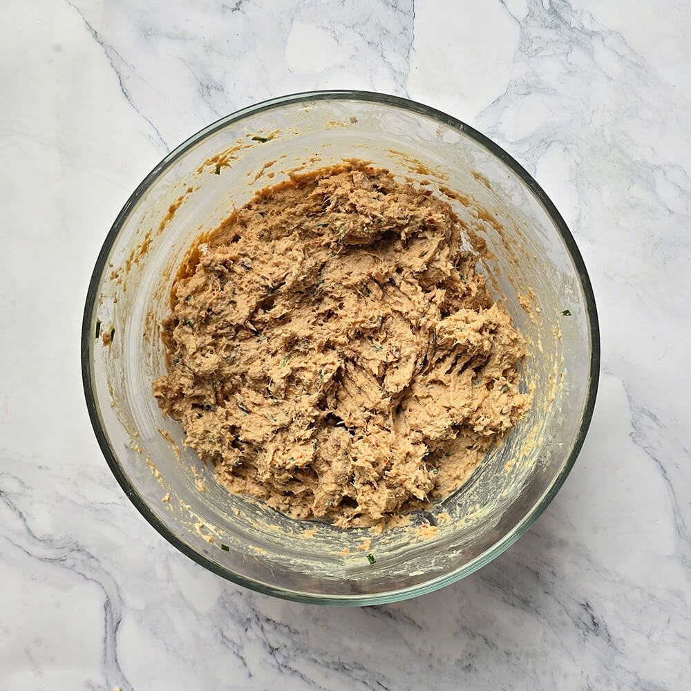 Des rillettes de thon dans un saladier en verre, sur un fond blanc marbré.