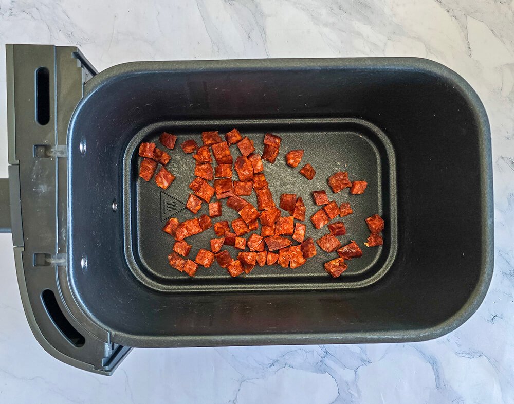 Du chorizo en dés dans la cuvette d'un Airfryer.