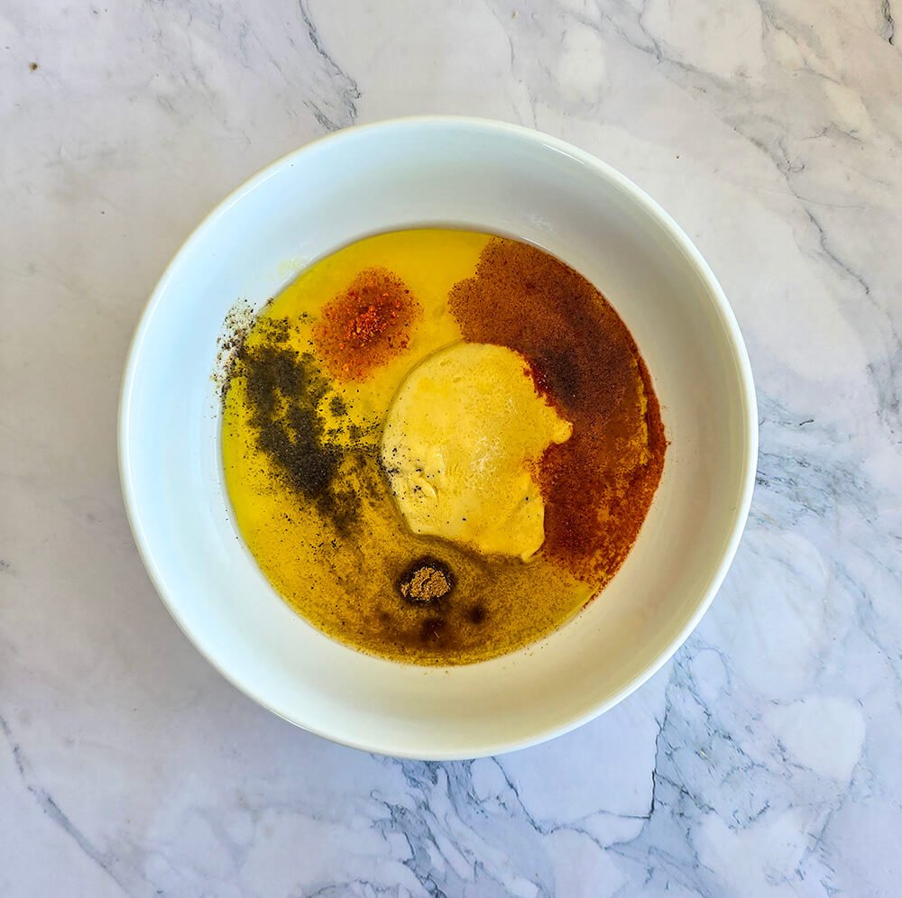 Des ingrédients dans un bol blanc pour préparer une sauce pour salade tex-mex.