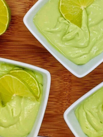 Des crèmes dessert citron vert dans des ramequins blancs, sur un fond en bois.