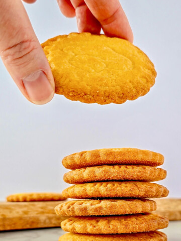 Pile de sablés bretons pur beurre faits maison, dorés et croustillants, présentés sur un plan de travail en marbre blanc.