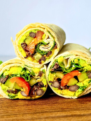 Des wraps végétariens haricots noirs et avocat sur une planche de bois.