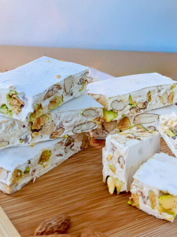 Des morceaux de nougat fondant sur une planche de bois.