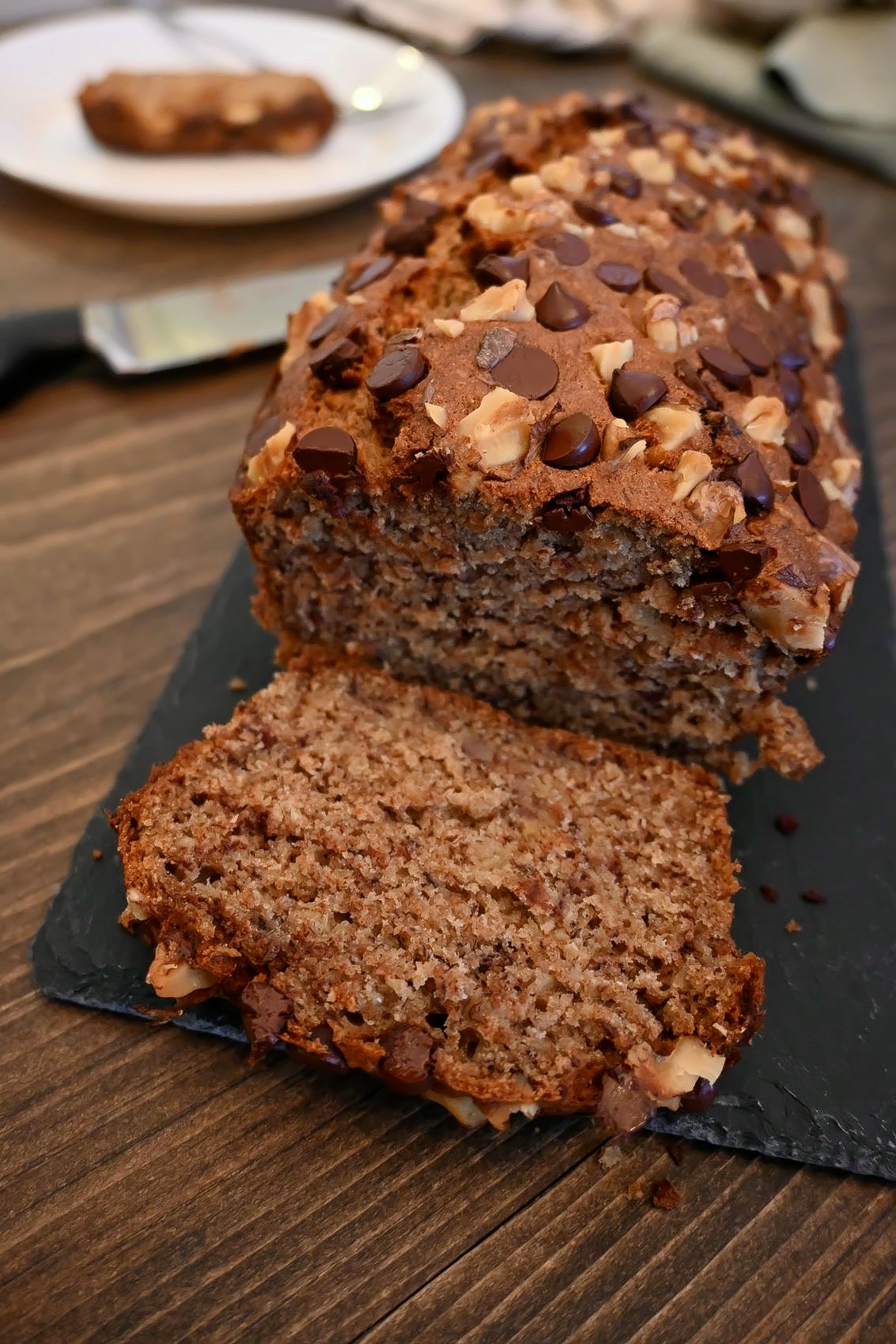 Un banana bread sur une planche de charbon, sur un fond en bois.