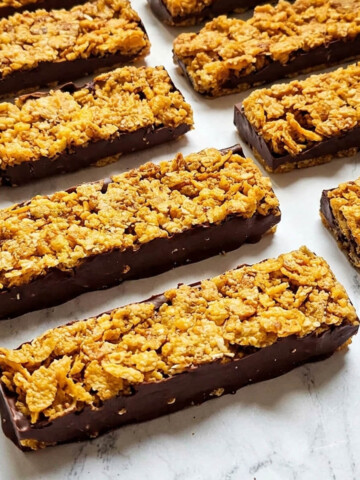 Barres de cornflakes au chocolat noir sur marbre, vue en angle montrant l'épaisseur du chocolat.