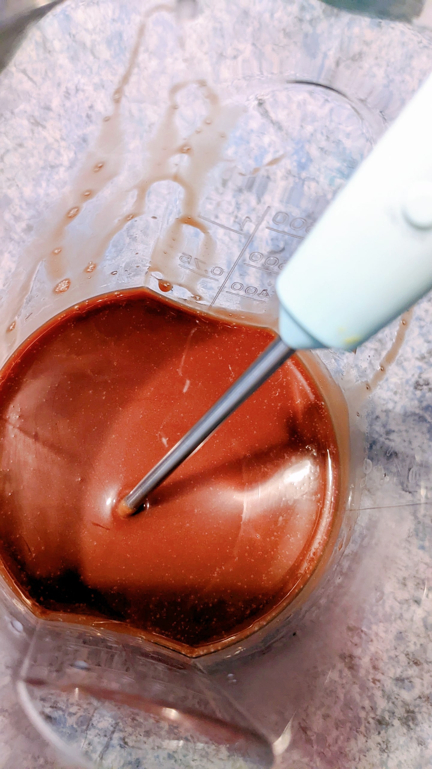 Vérifiation de la température du glaçage avec un thermomètre, pour une recette d'entremets au chocolat.