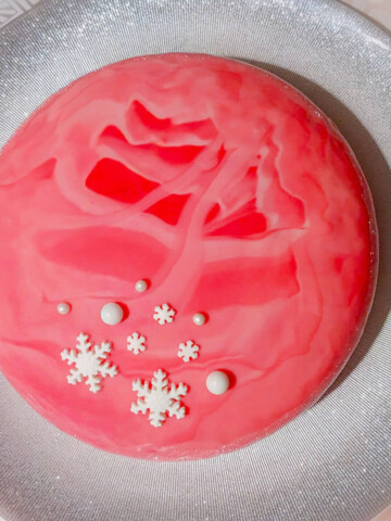 entremets avec un insert caramel et une mousse vanille, sous un glaçage miroir rose intense.