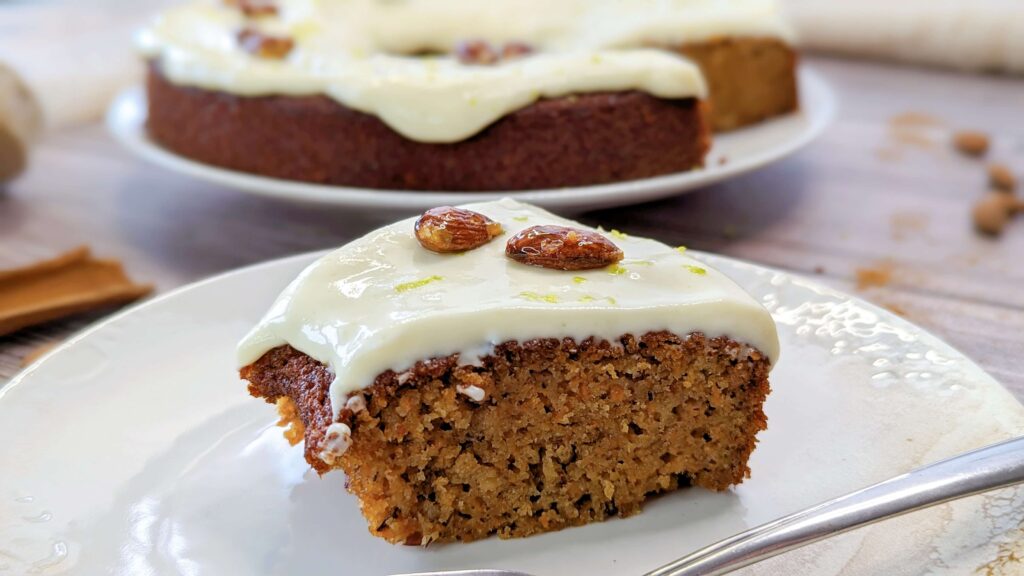 Part de carrot cake dans une assiette blanche sur un fond de couleur bois.