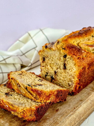 Un pain aux bananes moelleux aux pépites de chocolat sur une planche à découper.