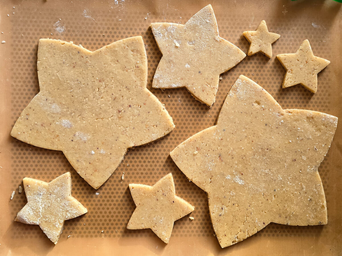 Des biscuits en forme d'étoile sur du papier sulfurisé brun clair.