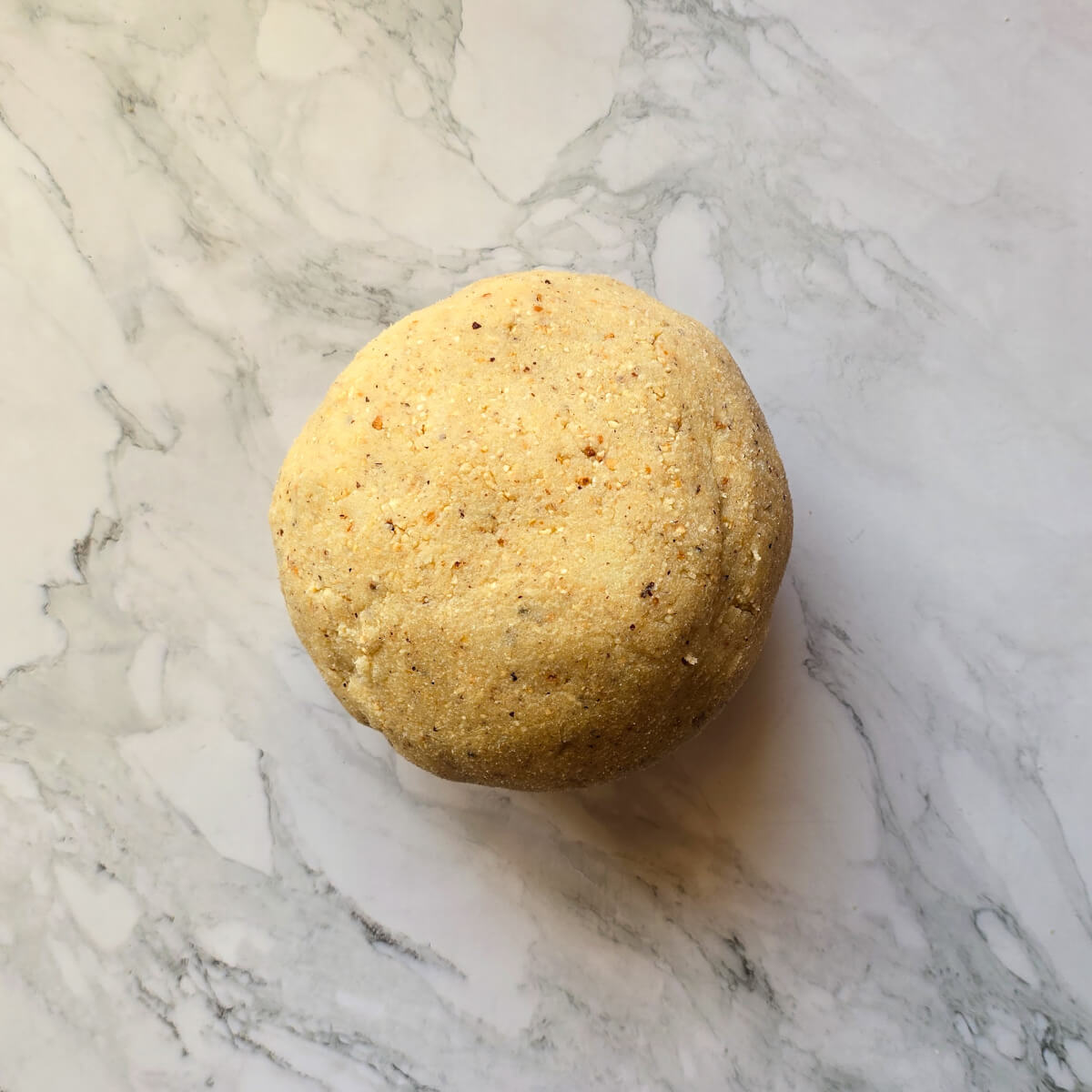 Une boule de pâte à biscuit s sur une surface blanc marbré.