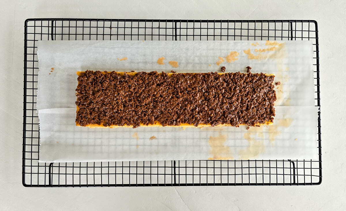 Praliné croustillant sur un biscuit joconde, sur une plaque de refroidissement munie de papier sulfurisé