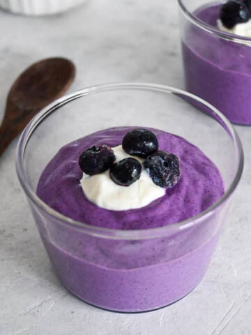 Porridge avoine-myrtilles en verrines sur fond gris clair.