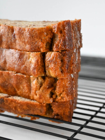 Des tranches de banana bread sur une plaque de refroidissement noire.
