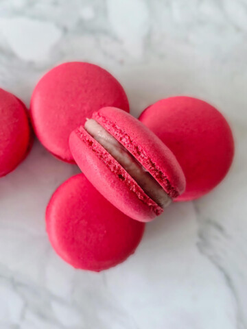 Des macarons ganache framboise sur un fond blanc.