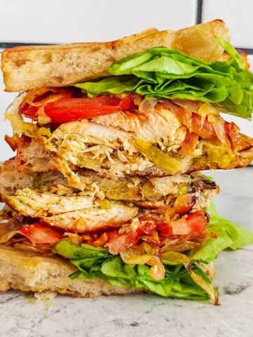 Un sandwich poulet pesto sur un fond gris clair marbré.