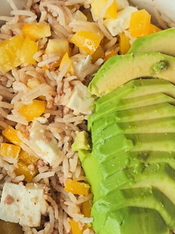Une salade de riz au thon, avec morceaux de poivrons jaunes, et rondelles d'avocat.