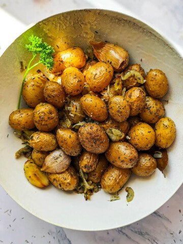 Des pommes de terre grenailles dans une assiette creuse blanche, sur fond blanc marbré.