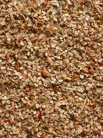 Du granola sans sucre sur une plaque de cuisson recouverte de papier sulfurisé.