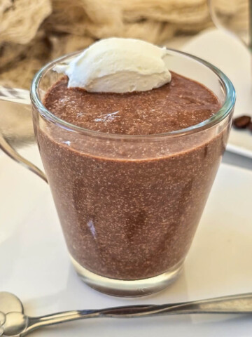 Une crème chocolat café dans un verre transparent, avec une touche de chantilly., petite cuillère sur le coté.