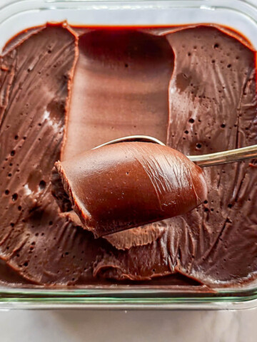 De la ganache au chocolat dans une boîte de conservation en verre, avec une cuillère qui enroule la ganache.
