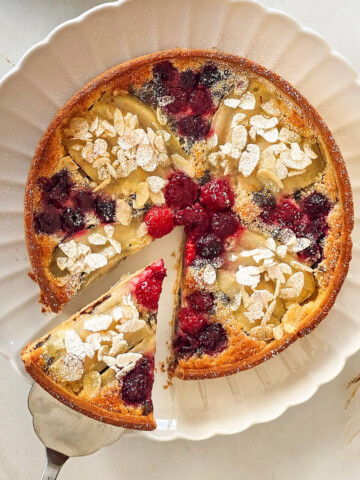 Une tarte amandine framboise sur une assiette blanche avec une spatule.