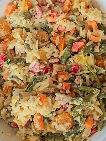 Une salade d'orzo méditerranéenne dans un plat blanc.