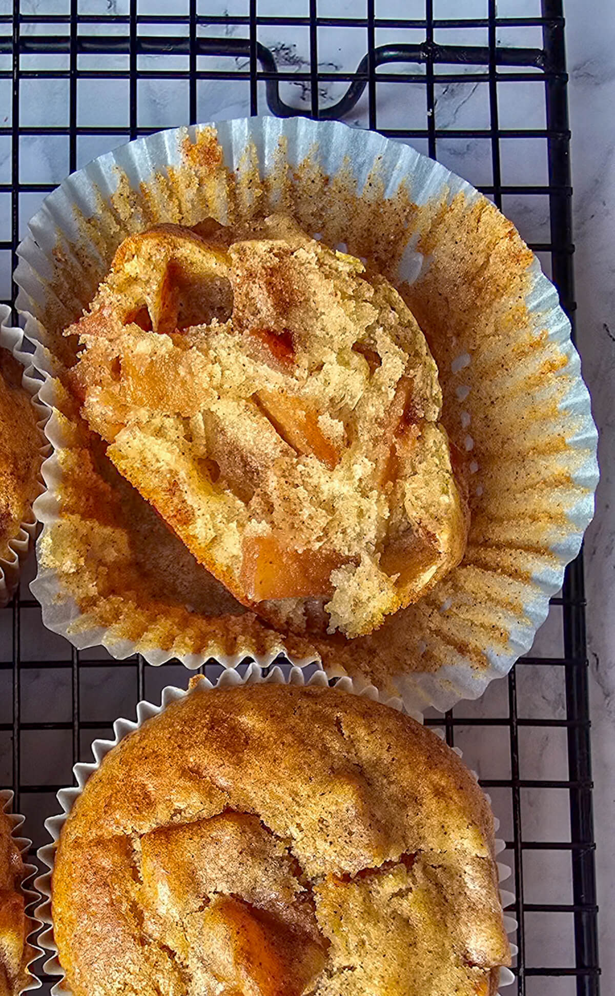Un muffin coupé en deux dans sa caissette en papier, sur une plaque de refroidissement noire.
