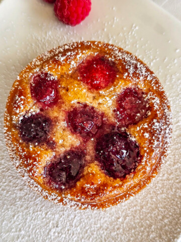 Une tartelette framboise sur une assiette blanche, avec un peu de sucre glace.