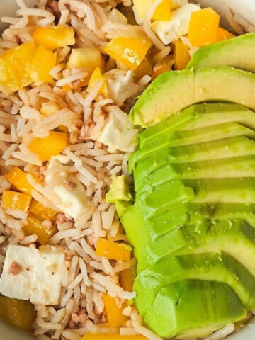 Une salade de riz au thon, avec morceaux de poivrons jaunes, et rondelles d'avocat.