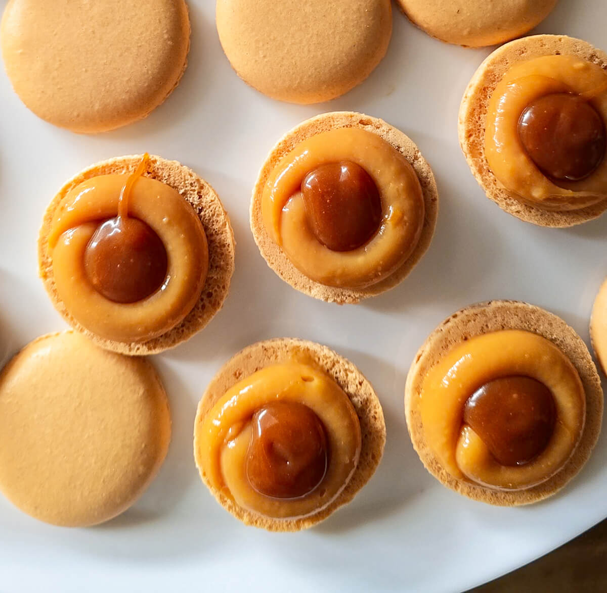 macarons-ganache-caramel-et-caramel-beurre-salé Des coques macarons au caramel fourrées de ganache au caramel, et au centre une pointe de caramel beurre salé.