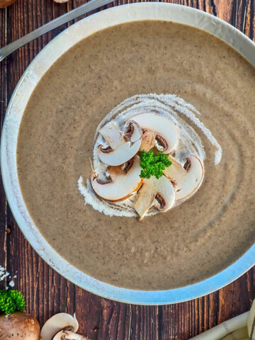 Bol de soupe aux champignons décoré de crème et de ciboulette fraîche.