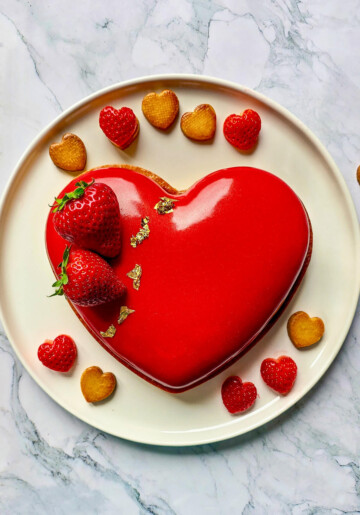 Un entremets fraise et chocolat blanc en forme de cœur, sur une assiette blanche.