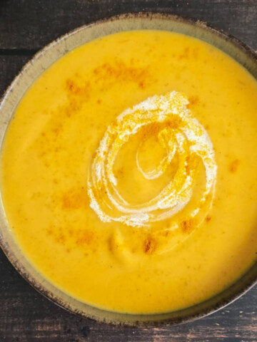 Recette de soupe aux pommes de terre et carottes dans un bol noir, sur fond en bois.