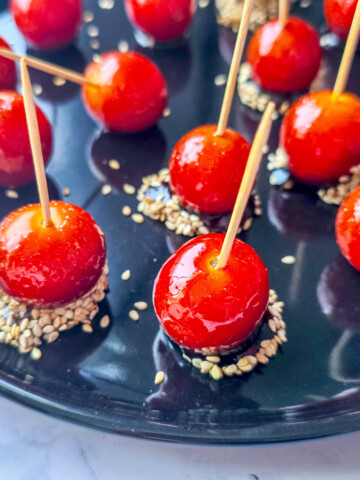 des tomates cerises sur un plat noir, avec des cure-dents.