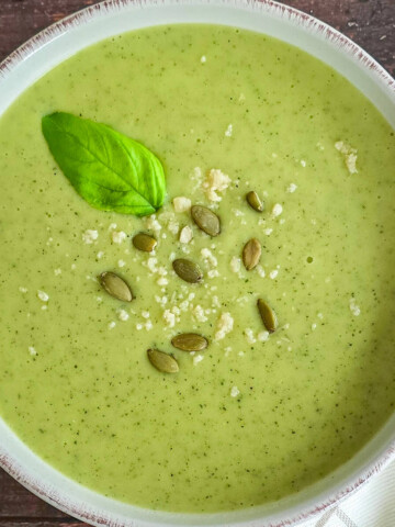 Un bol de velouté pommes de terre courgettes sur un fond boisé.